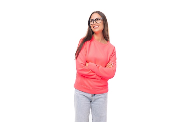 Pretty young brunette caucasian woman with straight hair is dressed in a pink sweatshirt and jeans