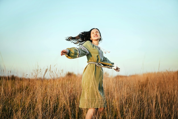 Pretty young brunette girl in long embroidery dress outdoor