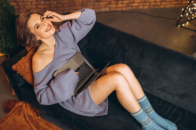 Pretty young brunette at home on the couch using a laptop