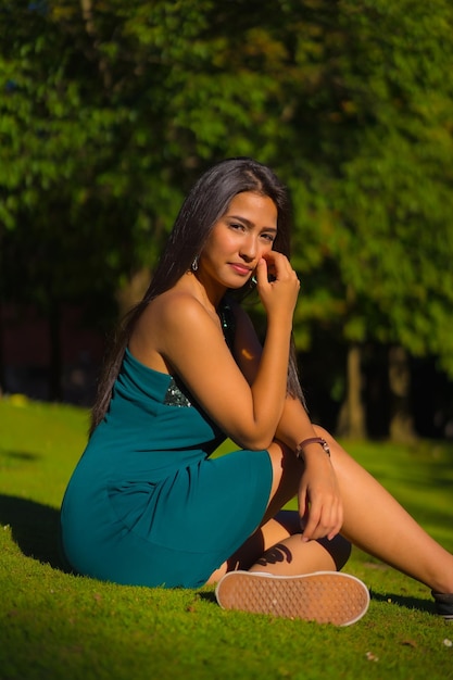 A pretty young brunette Latina with long straight hair wearing a tight green dress