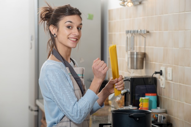 Foto donna castana abbastanza giovane che cucina nella cucina