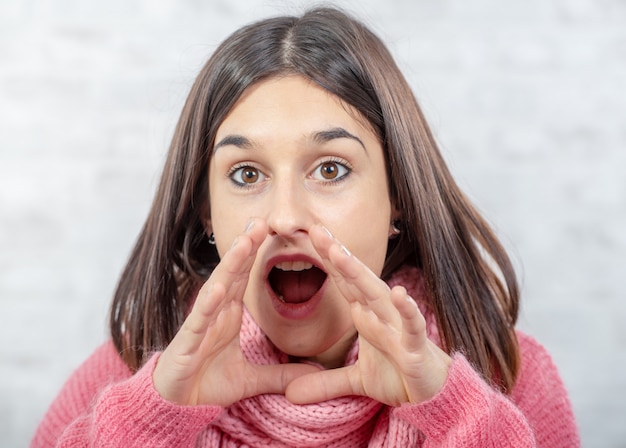 Pretty young brunette woman with hands around her mouth