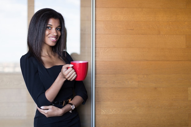 Pretty, young business lady in black strong suite hold red cup