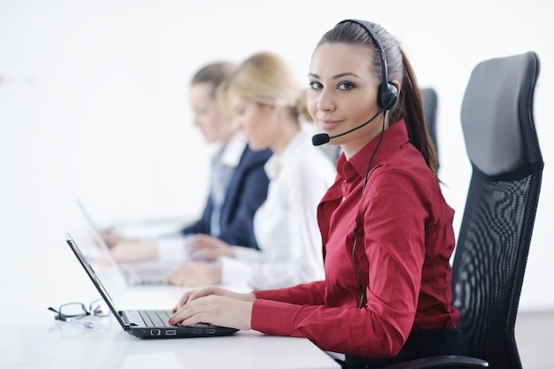 Pretty young business woman group with headphones smiling at you against white background