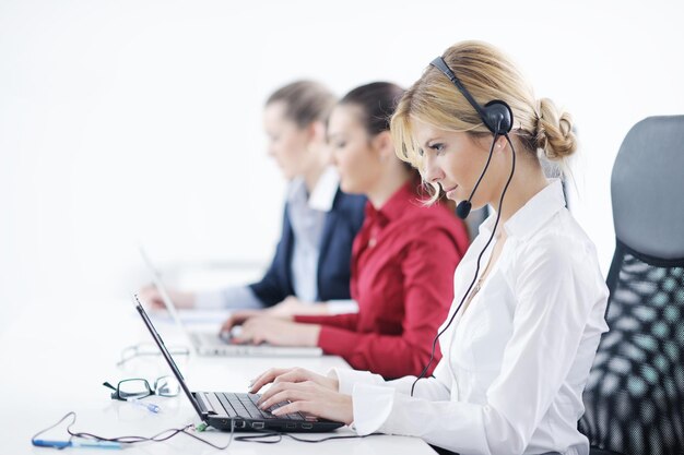 Pretty young business woman group with headphones smiling at you against white background