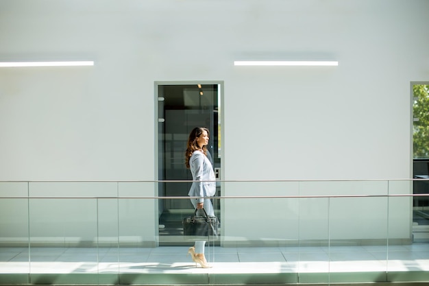 Pretty young business woman walking with briefcase in the office hallway