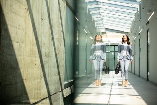 Pretty young business woman walking with briefcase in the office hallway