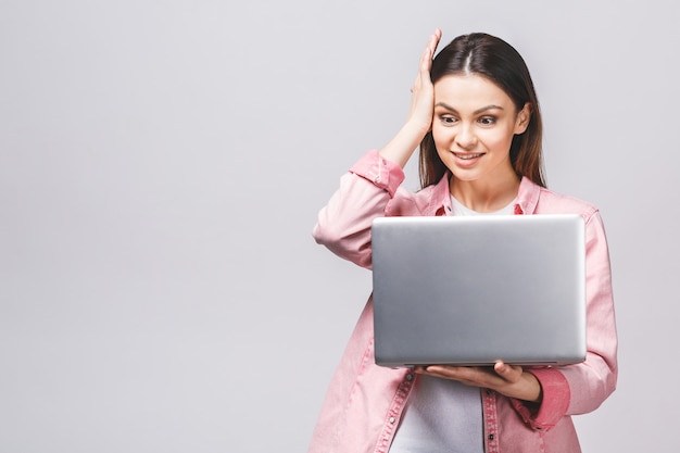 Donna di affari abbastanza giovane in computer portatile casuale della tenuta, isolato contro fondo whiate.