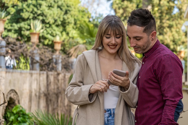 Photo pretty and young caucasian couple looking at a photo on the smartphone