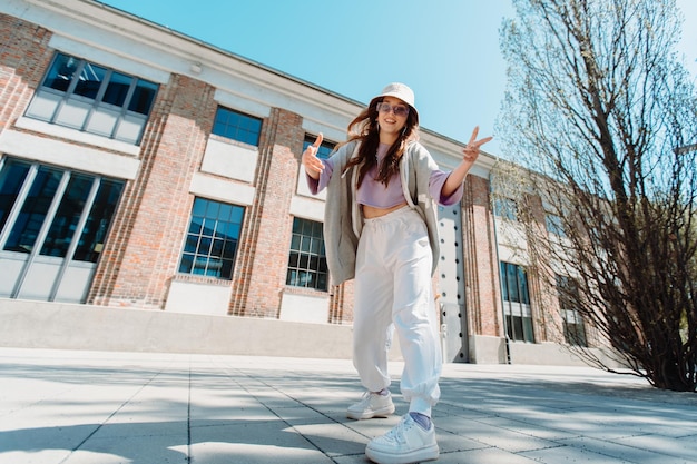 Довольно молодая кавказская девушка в хип-хоп одежде танцует под музыку под улицей