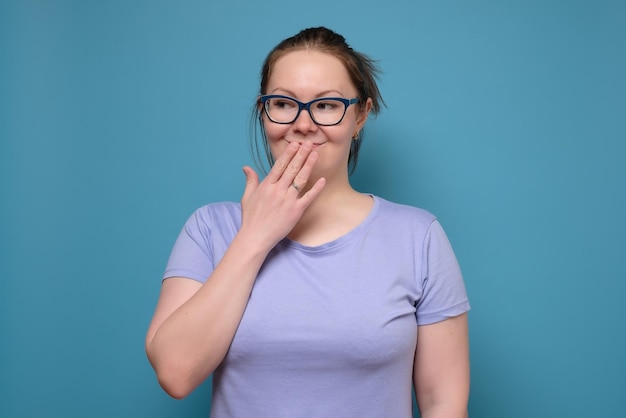 Pretty young caucasian woman with glasses with hand over mouth