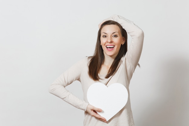 pretty young cheerful woman holding big white heart in hands isolated on white background. copy space for advertisement. with place for text. st. valentine's day or international women's day concept.