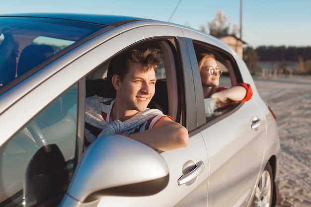 Coppie abbastanza giovani che guidano l'automobile alla riva di mare. donna e uomo divertirsi durante il viaggio. persone che viaggiano in automobile.