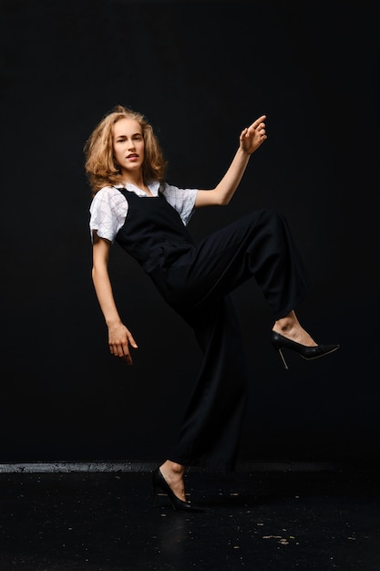 Pretty young fashion model in pantsuit and shirt takes a big step