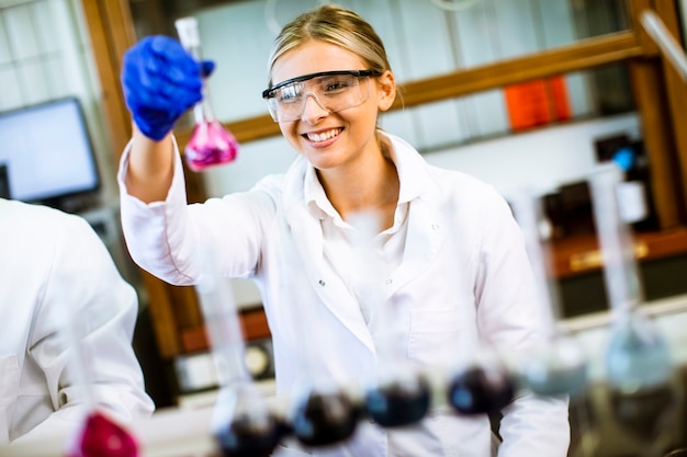 Pretty young female scientist examining liquid in biochemical lab