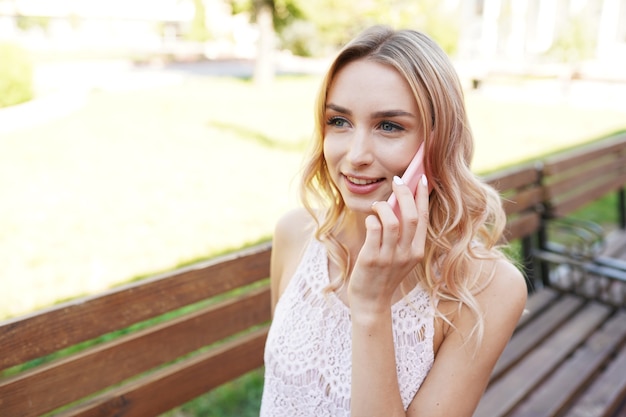 Pretty young female using white mobile phone at home smiling