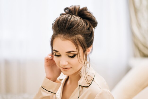 Pretty young girl.  Boudoir morning of the bride. Bride with luxurious hair and makeup. Accessories with feathers