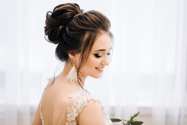 Pretty young girl.  Boudoir morning of the bride. Bride with luxurious hair and makeup. Accessories with feathers