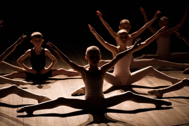 Foto ragazza graziosa e ragazzo seduto sul palco con stretching e formazione per i balli di balletto.