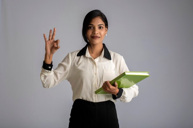 Pretty young girl holding book and posing on grey wall