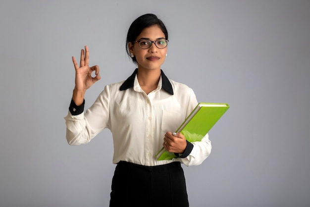 Pretty young girl holding book and posing on grey wall