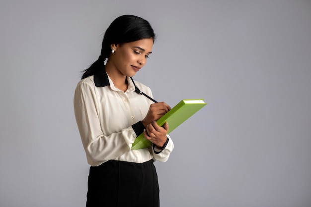 Pretty young girl holding book and posing on grey wall