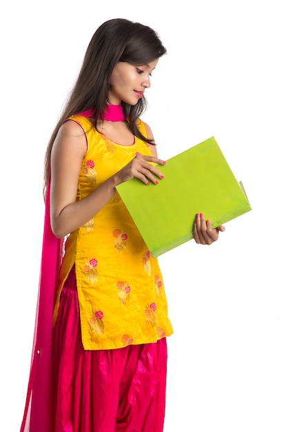 Pretty young girl holding book and posing on white background