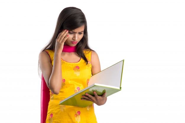 Pretty young girl holding book and posing on white background