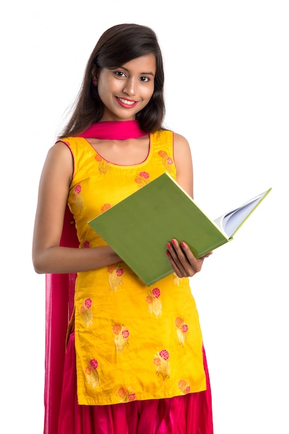 Pretty young girl holding book and posing on white surface