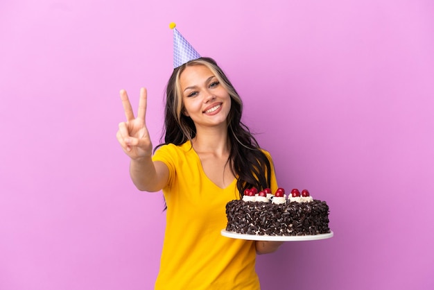 Pretty young girl holding a pizza over isolated blue wall shouting with mouth wide open