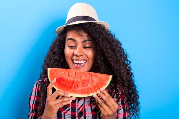 Ragazza graziosa che tiene fetta di anguria davanti al suo viso. ritratto della ragazza afroamericana sorridente isolata sana e felice