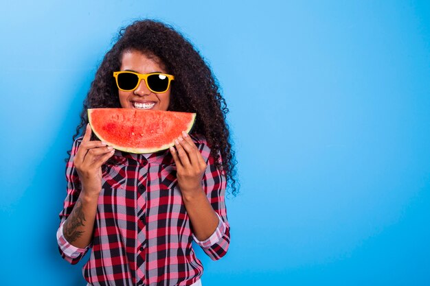 Ragazza graziosa che tiene fetta di anguria davanti al suo viso. ritratto della ragazza afroamericana sorridente isolata sana e felice