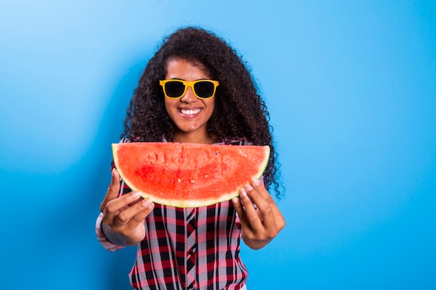 Ragazza graziosa che tiene fetta di anguria davanti al suo viso. ritratto della ragazza afroamericana sorridente isolata sana e felice