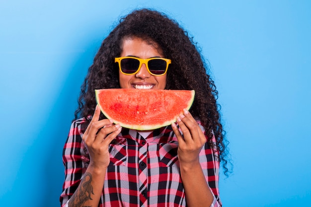 Photo pretty young girl holding slice of watermelon in front of her face. portrait of smiling african american girl isolated   healthy & happy