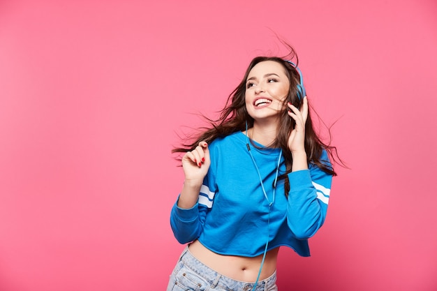 Pretty young girl posing at pink wall