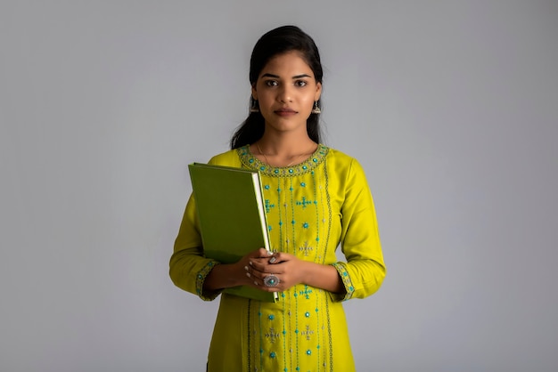 Pretty young girl posing with the book on grey wall