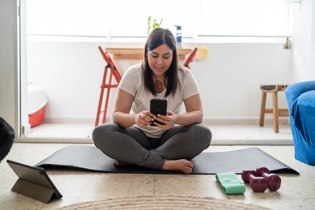 Foto bella ragazza che pratica esercizio e yoga nel suo soggiorno con un gatto nero