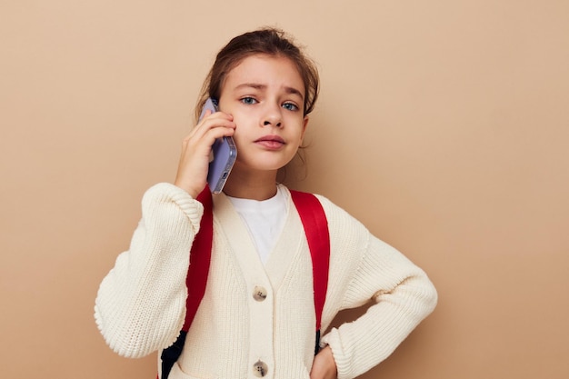 かなり若い女の子の女子高生のバックパックの携帯電話を手に子供時代は変更されていません