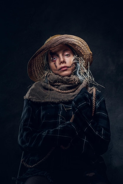 Pretty young girl in straw hat and oversized robe is performing as scarecrow.