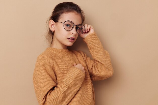 Pretty young girl in a sweater and posing glasses childhood unaltered