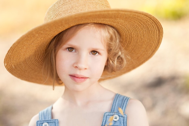 Pretty young girl wearing straw outdoors in meadow