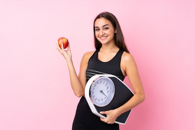 Pretty young girl with weighing machine with weighing machine and with an apple