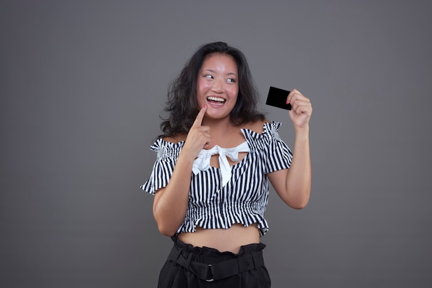 Pretty young happy and smiling chinese girl showing credit card