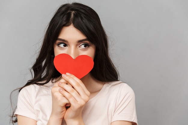 Pretty young lady covering face with heart