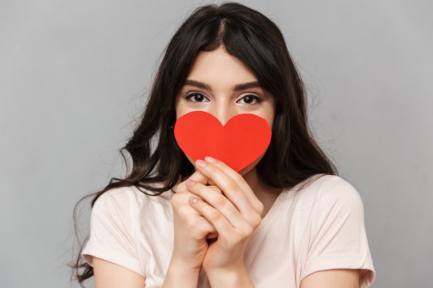 Pretty young lady covering face with heart