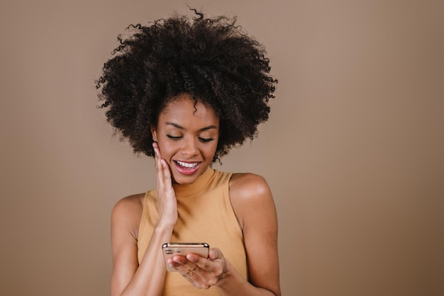 Pretty young Latin woman using smartphone standing on isolated pastel background feeling happy