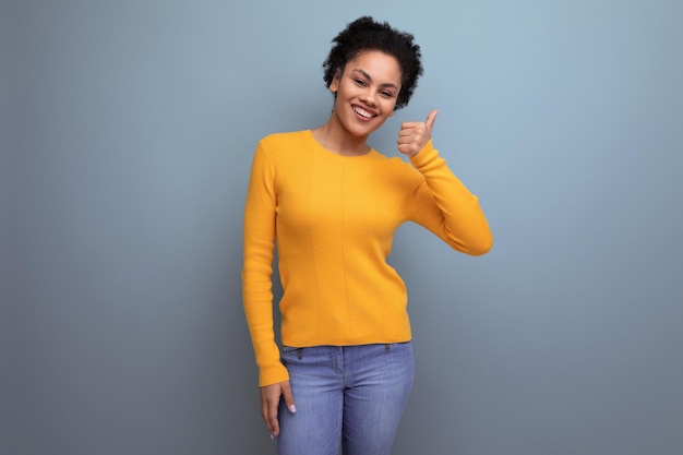 Piuttosto giovane donna latina con i capelli afro in posa sullo sfondo dello studio