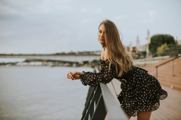 Pretty young long hair brunette woman standing on the riverside