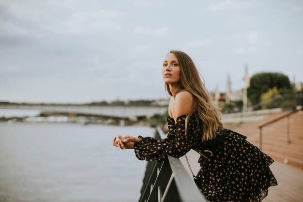 Pretty young long hair brunette woman standing on the riverside