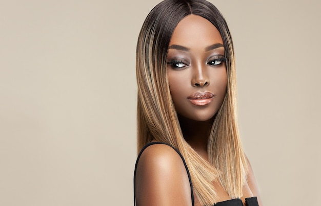 Una modella piuttosto giovane con un tono della pelle ricco di melanina e vibrante sta dimostrando un'acconciatura colorata e ben curata